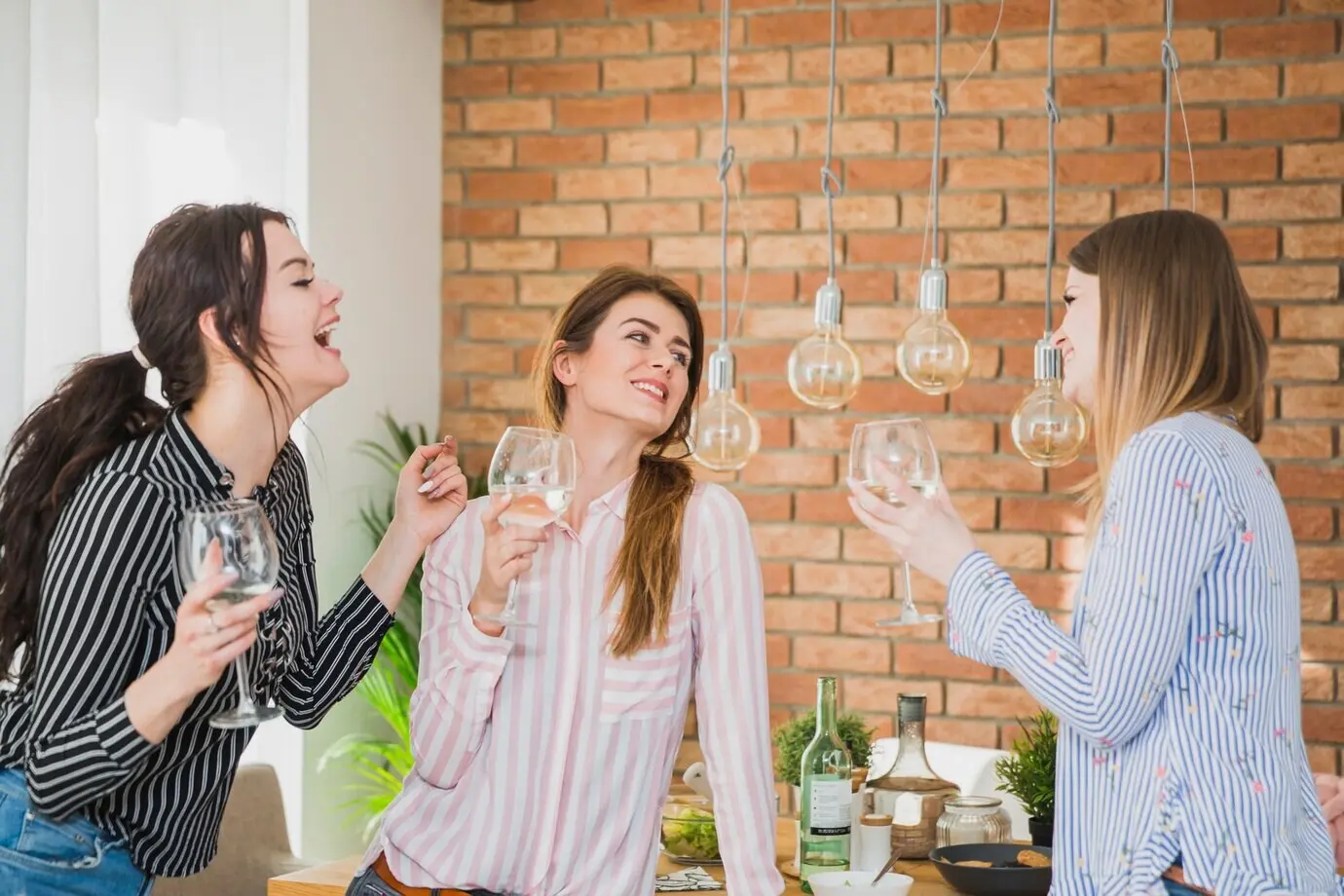 Женщины стоят дома со стаканами и беседуют.